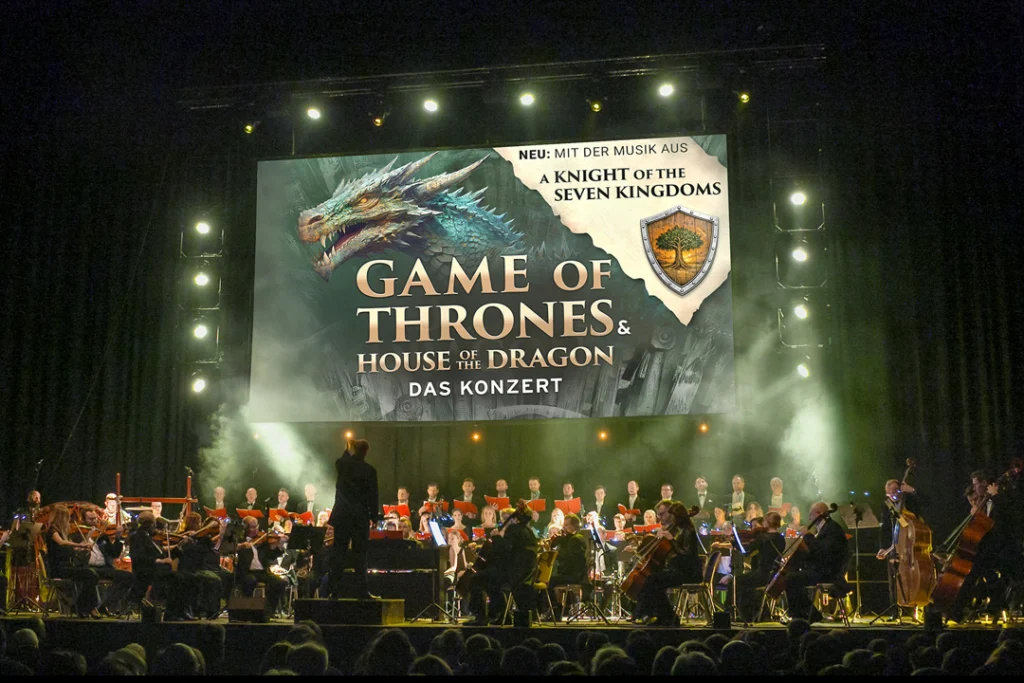 Teaserbild zu Game of Thrones & House of the Dragon mit Orchesteraufführung und Bühnenbeleuchtung.