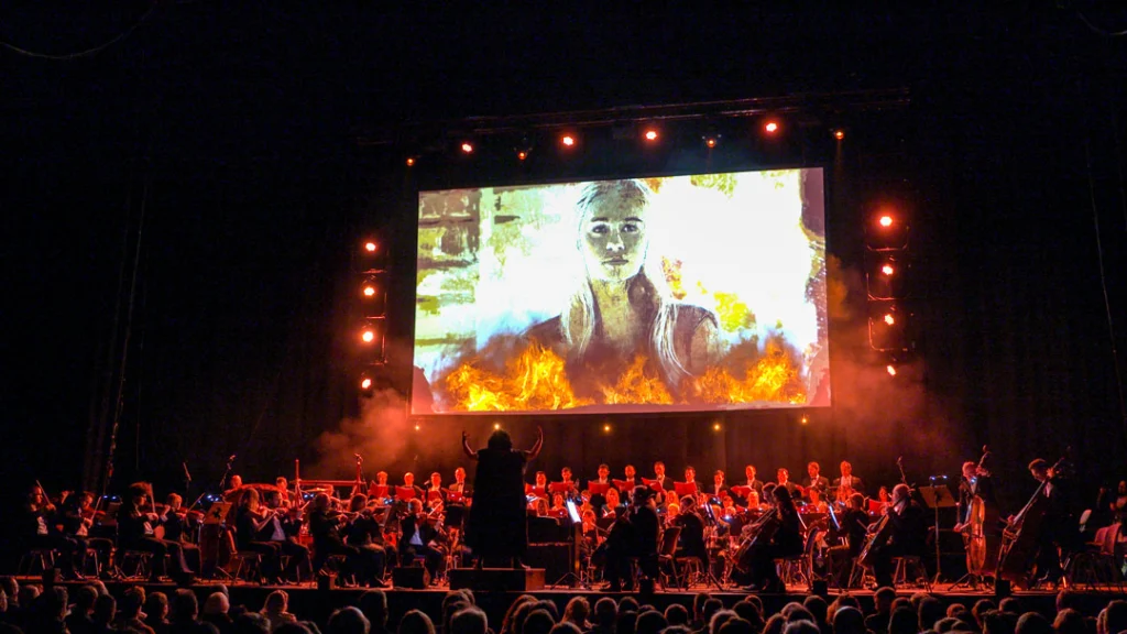 Teaserbild zu Game Of Thrones & House Of The Dragon mit Orchester und Projektion auf großer Leinwand.