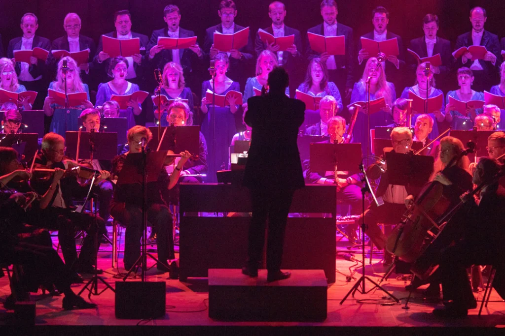 Choraufführung mit Sängern und Orchestermusikern auf der Bühne.