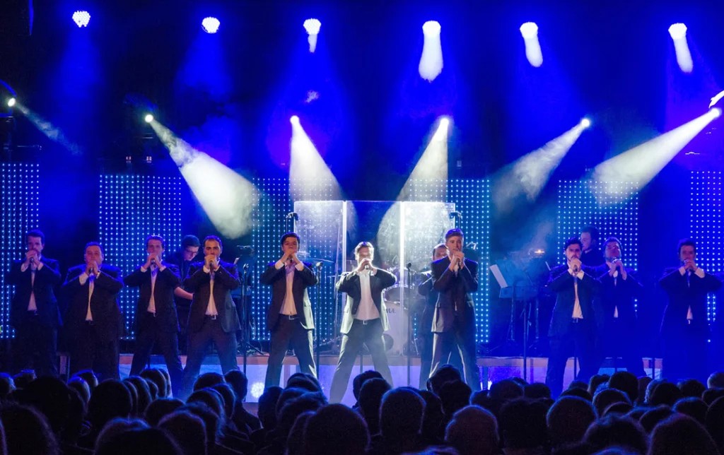 Live-Auftritt der 12 Tenors mit Sängern in Anzügen auf der Bühne.