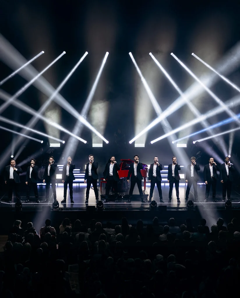 Teaserbild zu The 12 Tenors mit zehn Sängern auf der Bühne unter Scheinwerferlicht.