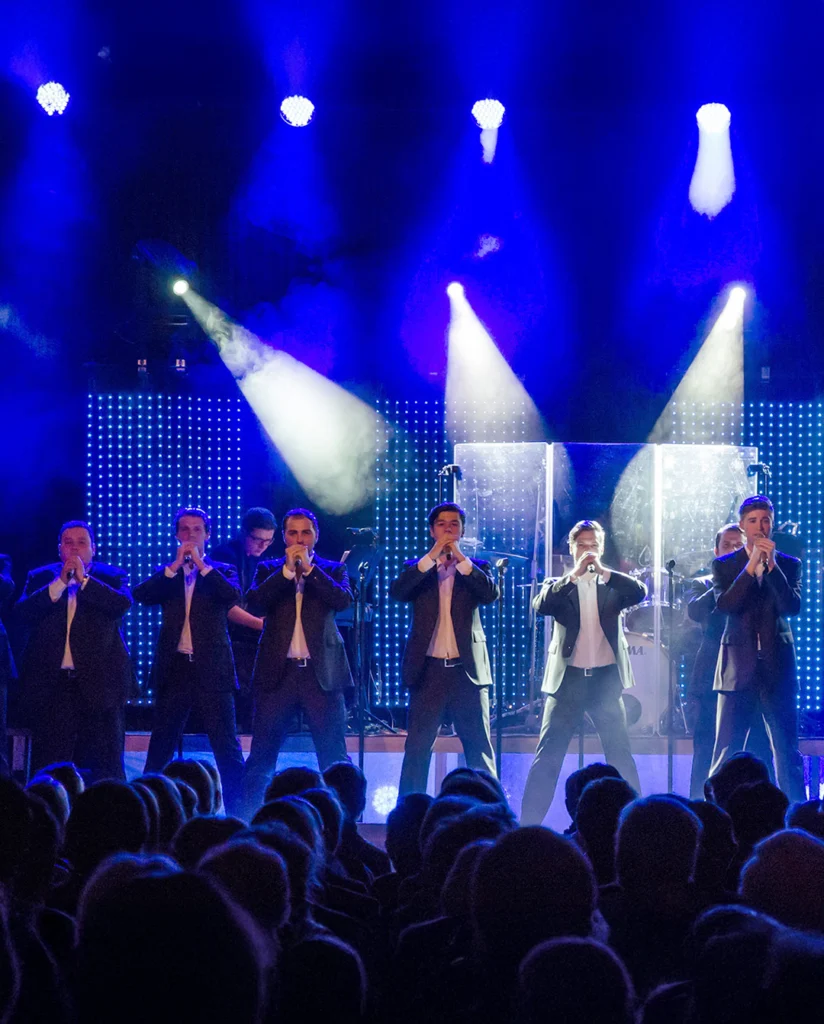 Teaserbild zu The 12 Tenors mit sechs Sängern auf der Bühne in Anzügen.