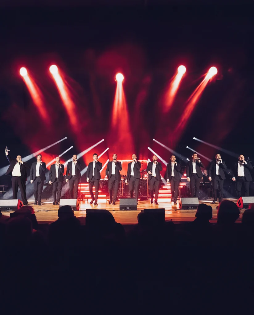 The 12 Tenors auf der Bühne mit Lichteffekten während eines Konzerts.
