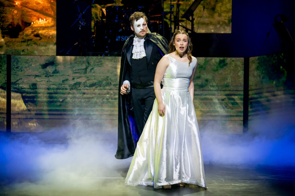 Szenenbild aus Das Phantom der Oper mit Darstellern in Kostümen auf der Bühne.