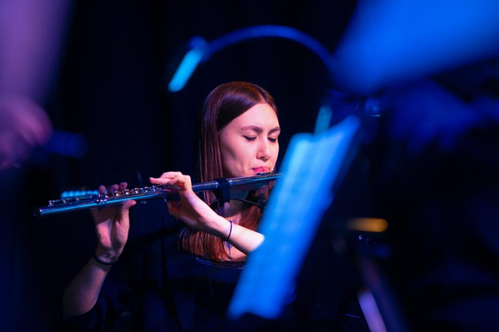 Musikerin spielt Flöte auf der Bühne mit blauer Beleuchtung.