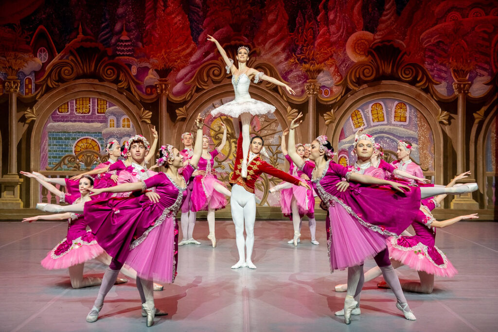 Tanzszene aus Der Nussknacker mit Balletttänzern in rosa Kostümen auf der Bühne.