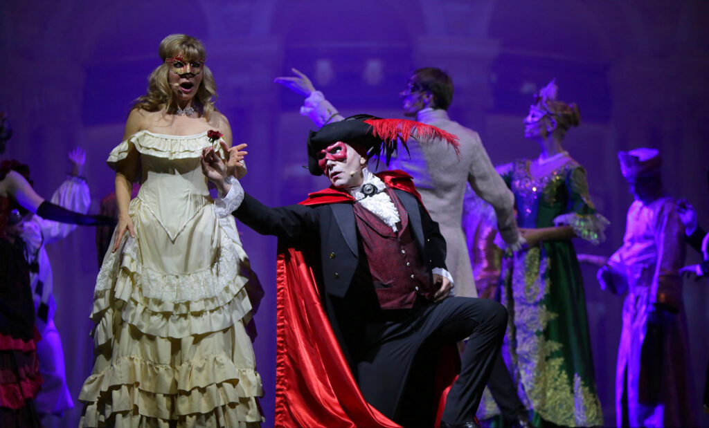 Szenenbild aus Das Phantom der Oper mit Darstellern in Kostümen auf der Bühne.