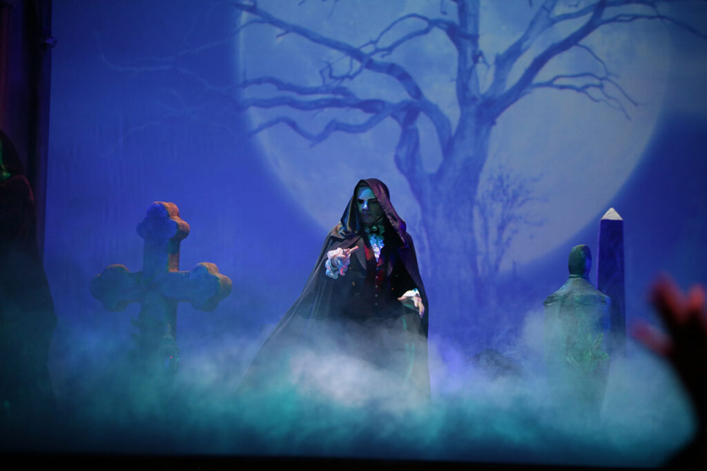 Teaserbild zu Das Phantom der Oper mit einer mystischen Szene und einer Figur in einem Umhang vor einem Mond.