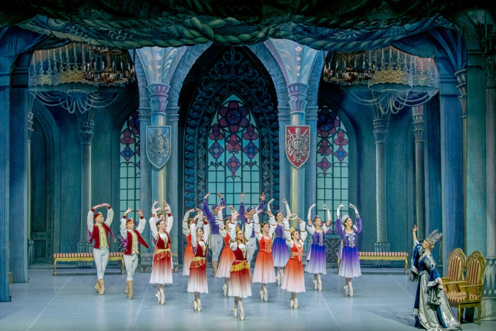 Teaserbild zu Schwanensee mit tanzenden Balletttänzern in farbenfrohen Kostümen auf einer Bühne.
