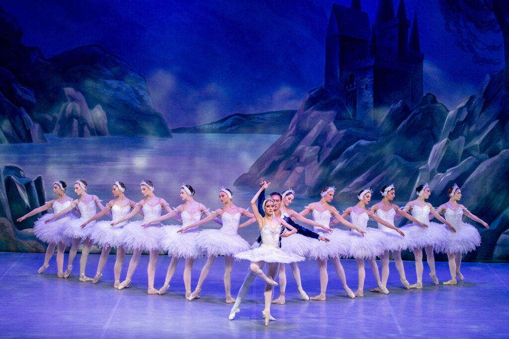 Tanzende Ballerinas in weißen Tutus auf der Bühne von Schwanensee.