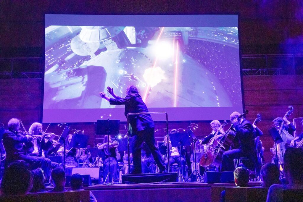 Teaserbild zu The Music of Star Wars mit Orchester und Projektion einer Weltraumszene.