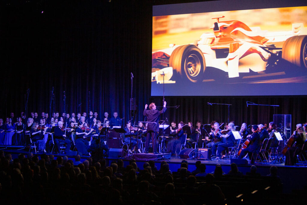 Teaserbild zu The Magic of Hans Zimmer mit Orchester und großem Bildschirm im Hintergrund.