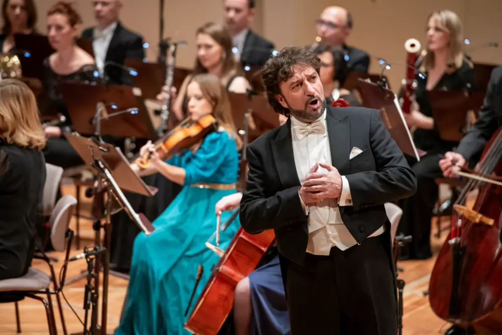 Sänger bei der Verdi Gala auf der Bühne, umgeben von einem Orchester.