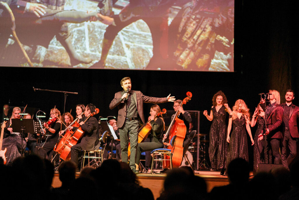 Teaserbild zu Highlights der schönsten Musicals mit einem Sänger und Orchester auf der Bühne.