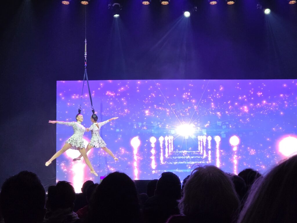 Teaserbild zu Eiskoenigin 4 mit zwei Tänzerinnen in glitzernden Kostümen auf der Bühne.